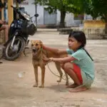 A girl is sitting on the ground with her dog.