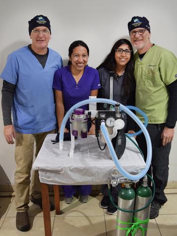 A group of people standing around a table with some medical equipment.