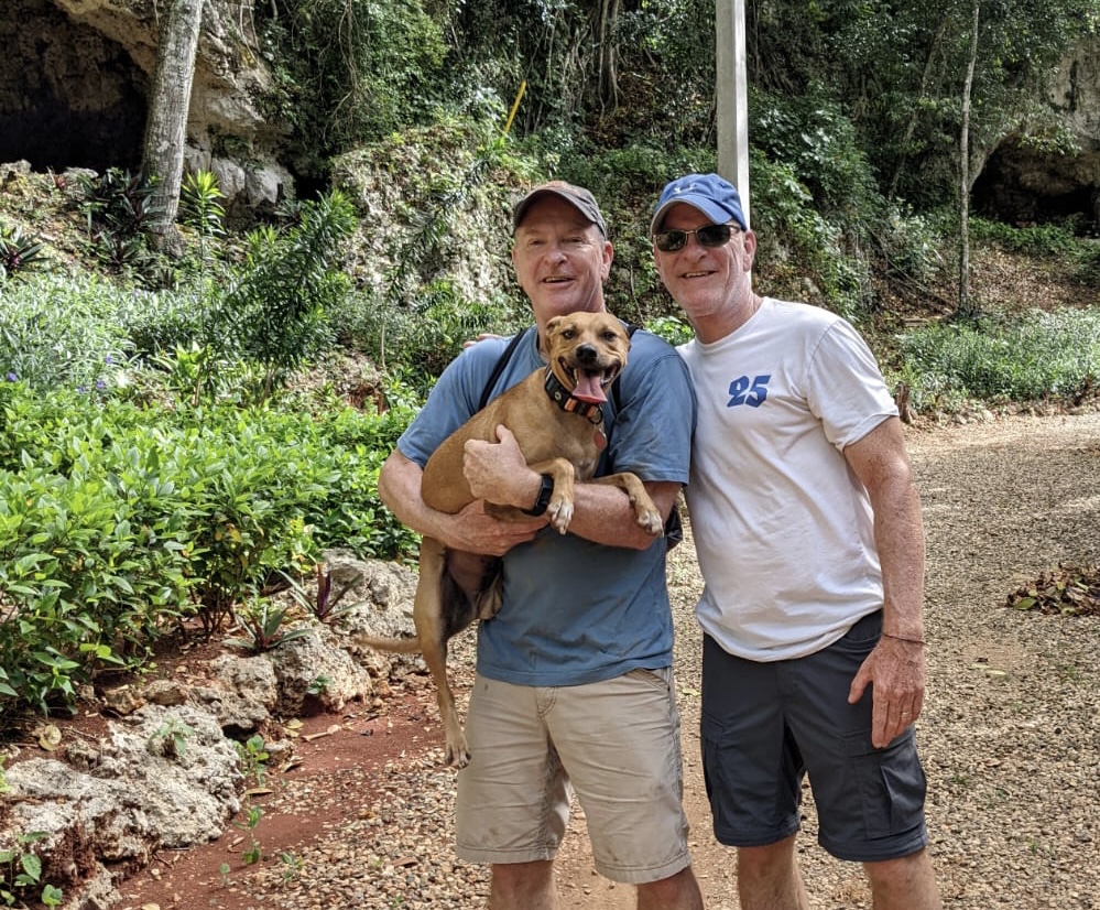 Two men and a dog standing next to each other.