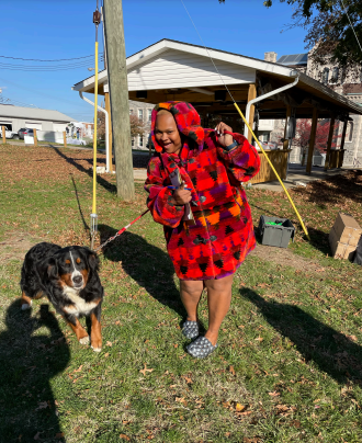 A woman in red and black is holding onto two dogs