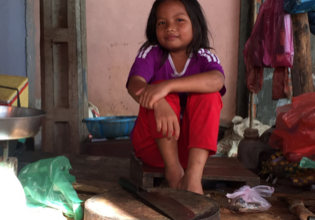 A young girl sitting on the floor of her home.