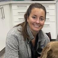 A woman sitting in front of a brown dog.