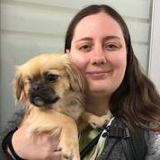 A woman holding a small dog in her arms.